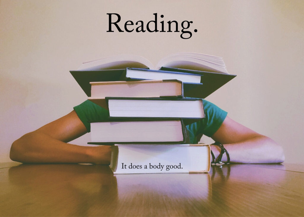 Photo of a person sitting at a table behind a pile of books. The top book is open. The overlaid text reads: Reading. It does a body good.